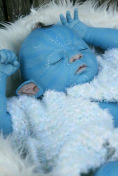 a baby with blue skin and white furs is laying on his side in the snow