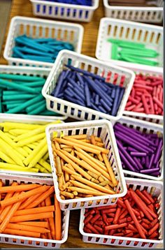 many different colored crayons in baskets on a table