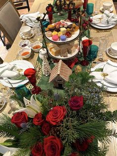 a table set for christmas dinner with red roses