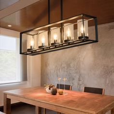 a dining room with a wooden table and four lights hanging from it's ceiling