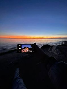 someone taking a photo with their cell phone at sunset