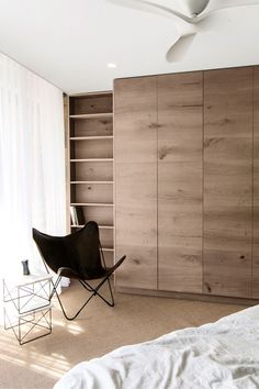 a bedroom with a bed, chair and bookcase