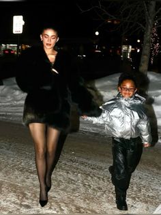 a woman walking next to a little boy in the snow