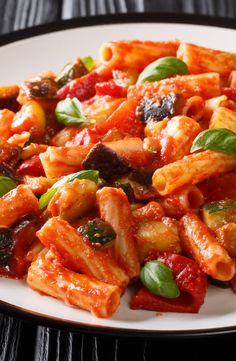 a white plate topped with pasta covered in tomato sauce and spinach sprinkled on top