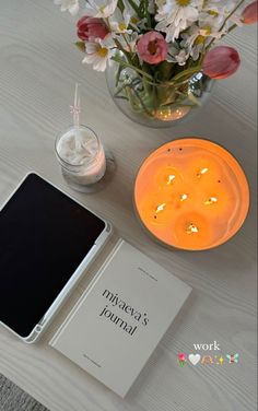 a table topped with a book and a candle next to a vase filled with flowers