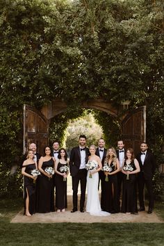 a bride and groom with their bridal party in front of an arch covered by ivy