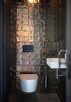 a bathroom with a toilet and sink next to a wall made of tiles that looks like bricks