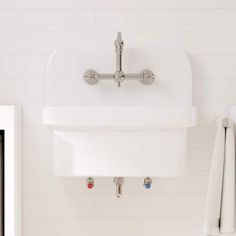 a white sink mounted to the side of a wall next to a towel dispenser