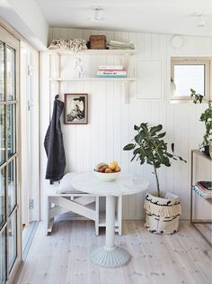 a white table sitting in the middle of a room next to a potted plant