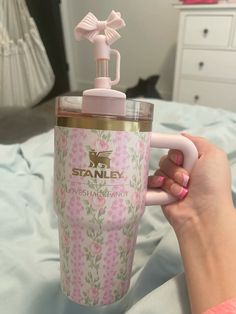 a woman is holding a pink and white cup with a handle on it that has a bow on the top