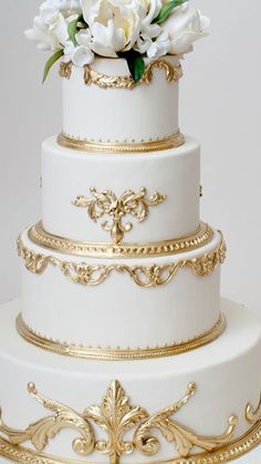 a white and gold wedding cake with flowers on top is featured in the instagram