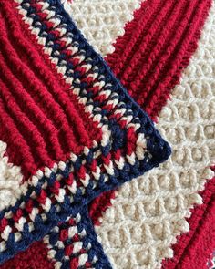 a red white and blue crocheted blanket laying on top of a tablecloth