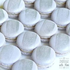 several white macaroons are sitting on a plate with some frosted ones in the middle