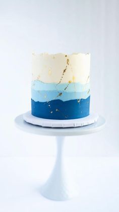 a white cake with blue and gold icing on a plate in front of a white background