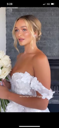 a woman in a wedding dress holding a bouquet of flowers and looking at the camera