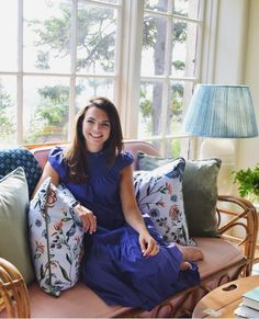 a woman sitting on top of a couch with lots of pillows in front of her