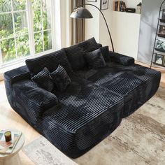 a large black couch sitting in a living room next to a window