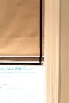 an open window with a tan roman blind