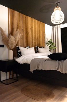 a bedroom with black and white bedding, wooden headboard, pillows and rugs