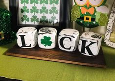 some dice that are sitting on top of a wooden board with shamrock decorations in the background