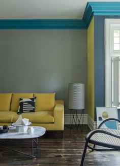 a living room with yellow couches and blue trim on the walls in front of a window