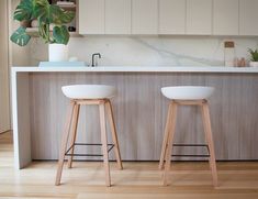 two white stools sitting in front of a counter top next to a potted plant