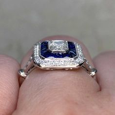 a woman's hand holding a blue and white diamond ring