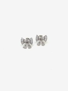 We fell in love with these sweet sterling bow earrings. Although not diamonds - these Zircon baguette stones shine and glisten just like them! The 3-D nature of the bows is super unique and perfect for dressing up for a coquette moment. Materials: Sterling silver CZ stones Measurements: 1/2" wide Notes: Sold as a pair Sterling Silver White Gold Earrings With Bow, White Gold Sterling Silver Earrings With Bow, Formal Bow Earrings With Cubic Zirconia, Formal Bow Earrings In Cubic Zirconia, White Gold Bow Earrings For Formal Occasions, Elegant White Gold Earrings With Bow, Luxury Silver Jewelry With Bow Detail, Luxury Silver Jewelry With Bow, Anniversary White Gold Bow Earrings