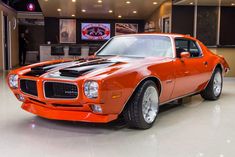 an orange muscle car parked in a showroom