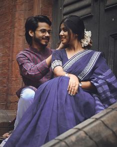 a man standing next to a woman in a purple sari on the steps of a building