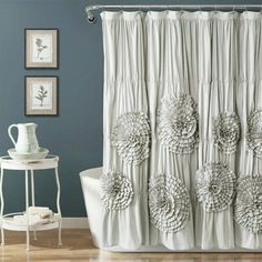 a white bath tub sitting next to a shower curtain with flower decorations on the side