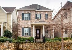 a stone wall in front of a brick house