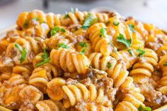 a bowl full of pasta with meat and parsley on top is shown in this image