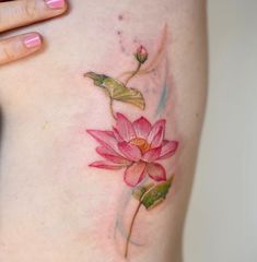 a woman's stomach with a pink flower tattoo on her left side ribcage