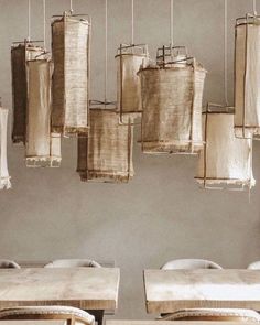 several pieces of burlap hanging from the ceiling above a table and bench with pillows on it