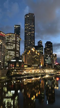 the city is lit up at night and reflecting in the water