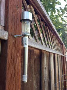 an outdoor light attached to the side of a wooden fence