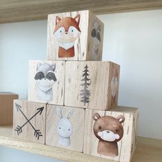 wooden blocks with animals painted on them sitting on top of a shelf in a room