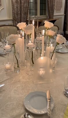 the table is set with white roses and candles