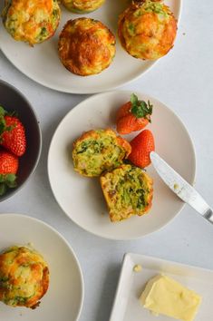 three white plates with muffins and strawberries on them next to some butter