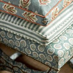 four pillows stacked on top of each other in different colors and patterns, all with decorative designs