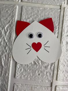 a paper cut out of a cat's face on a white tile wall with eyes and nose