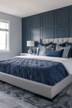 a bedroom with blue and white bedding in the corner, along with two lamps on either side of the bed