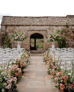 an outdoor ceremony setup with white chairs and pink flowers on the aisle, surrounded by greenery