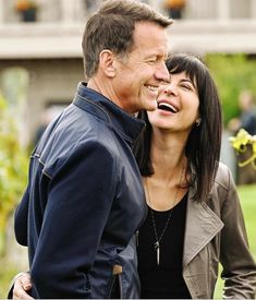 a man and woman standing next to each other in front of a building with flowers