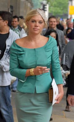 a woman in a green dress walking down the street with other people behind her stock photo