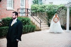 a bride and groom standing in front of a brick building with steps leading up to them