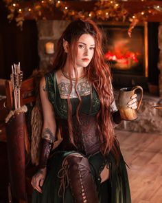 a woman with long red hair sitting in a chair holding a cup