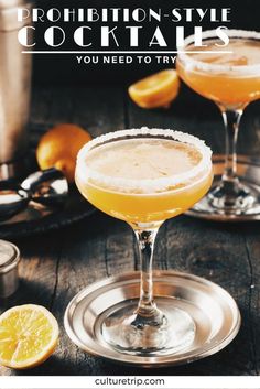 two glasses filled with orange cocktails sitting on top of a wooden table