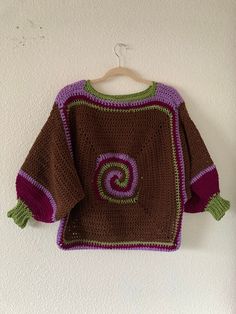 a crocheted sweater hanging on a wall